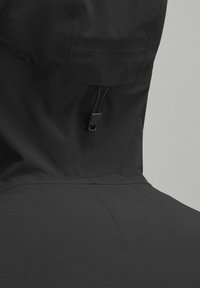 Sort vandtæt jakke med høj krave og justerbar snor, glat tekstur og minimalistisk design uden yderligere mønstre.