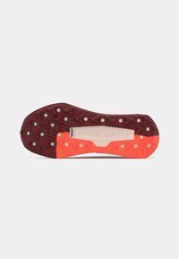 Sport shoe outsole featuring a brown and orange colorway, with textured rubber for traction and a brand logo embossed in the center.