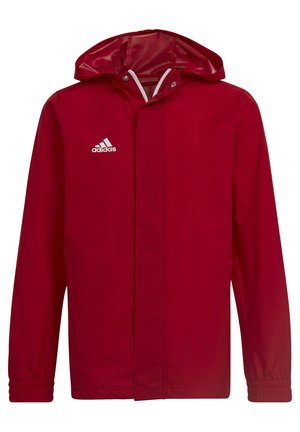 Veste imperméable rouge avec capuche, poignets élastiques, bandes blanches et logo brodé blanc sur la poitrine gauche. Texture douce.