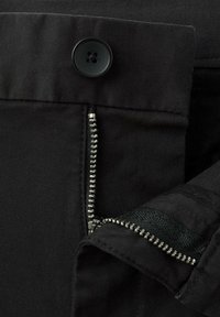 Czarna tkanina z częściowo otwartym metalowym zamkiem błyskawicznym i czarnym guzikiem na cztery dziurki na pasku ubrania.