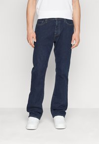 Mörkblå raka jeans tillverkade av denim, med en klassisk femficksdesign och diskret sömnad. Bärs med vita sneakers.