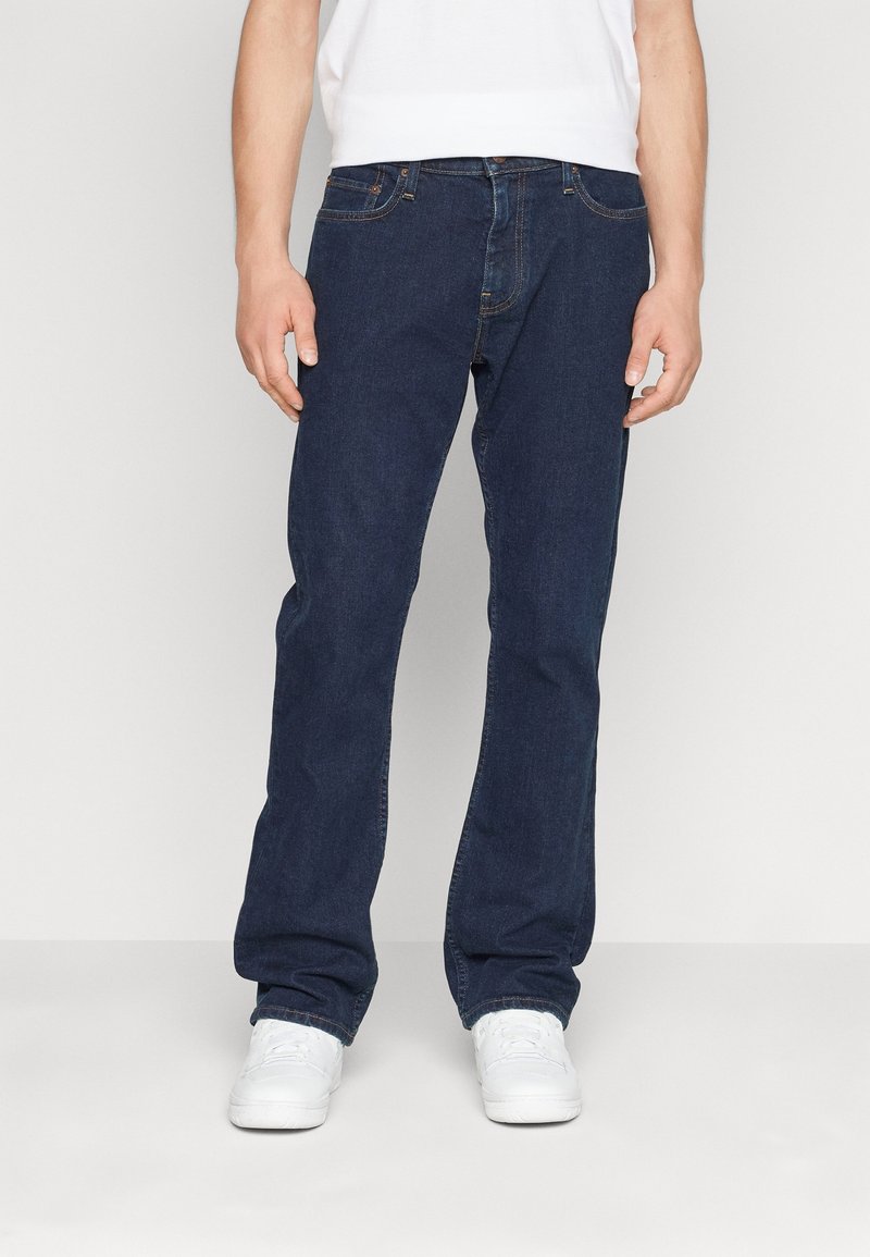 Mörkblå raka jeans tillverkade av denim, med en klassisk femficksdesign och diskret sömnad. Bärs med vita sneakers.