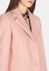Cappotto in misto lana rosa con colletto a punta, design monopetto e due bottoni. Tessuto liscio con vestibilità sartoriale e tasche laterali.