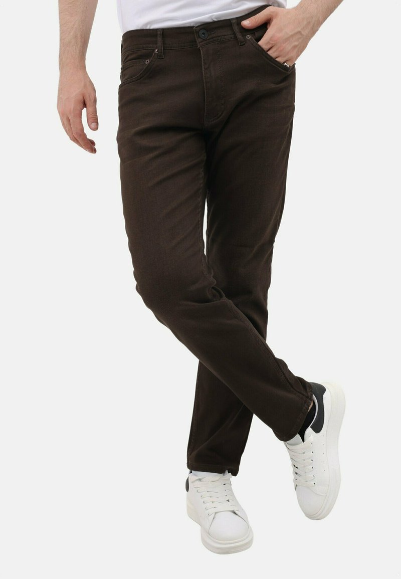 Bruine denim jeans met een slim fit, met voorzakken en een knoopsluiting, gecombineerd met witte sneakers en een eenvoudig wit t-shirt.