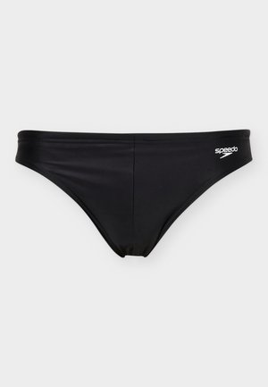 Sorte badebukser for menn med Speedo-logo på høyre hofte, flate sømmer, og lav midje mot en ensfarget lys bakgrunn.