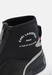 Czarne sneakersy za kostkę z zamkiem, białym napisem "Karl Lagerfeld Paris 21 Rue St-Guillaume" oraz wytłoczonym napisem "KARL" na podeszwie.