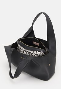 Czarna skórzana torba tote z teksturowanym wykończeniem, przestronnym wnętrzem z wyściełaniem o wzorze oraz akcentami w kolorze złotym.