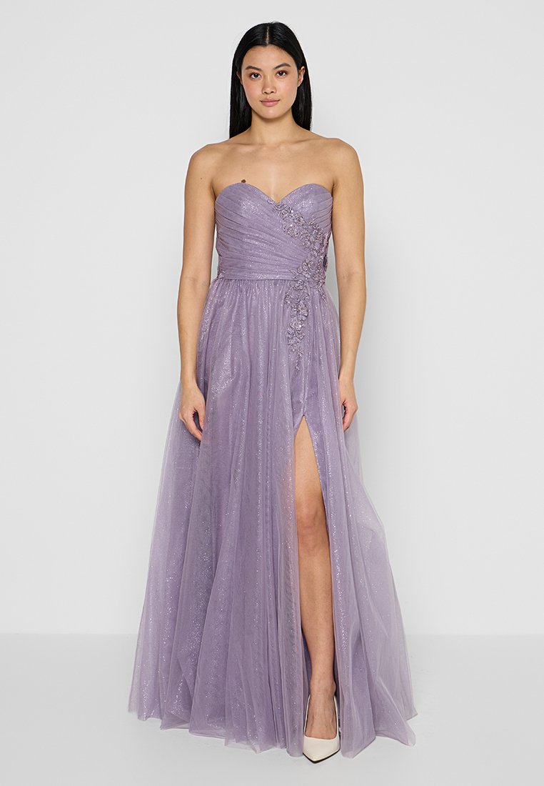 Sukienka wieczorowa bez ramiączek, długa do ziemi, w lilakowym tiulu, z marszczonym materiałem, bocznym rozcięciem oraz kwiatowymi zdobieniami w talii.