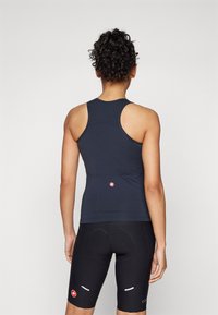 Ermeløs sort treningstopp med racerback-design, tettsittende silhuett og logo-detallering på nedre rygg, kombinert med sorte sykkelshorts.