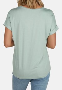 T-shirt vert menthe à manches courtes avec des poignets retroussés, en tissu doux, coupe relaxée et ourlet arrondi, présenté de dos.