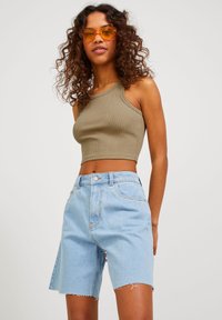 Top scurt khaki cu dungi, cu bretele late, asortat cu pantaloni scurți din denim albastru deschis, având margini desfăcute și un design clasic cu cinci buzunare.
