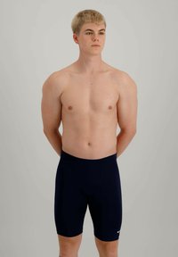 Shorts de bain navy en tissu extensible, offrant un ajustement près du corps, une texture lisse et un petit logo blanc sur le bas à l'avant.