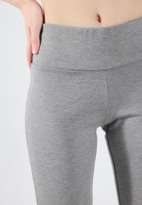 Grå tights med høy, jevn midje. Laget av mykt, elastisk stoff. Har en ensfarget tekstur uten mønstre eller detaljer.