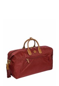 Sac de sport bordeaux en tissu durable, doté de poignées en cuir marron et d'une poche zippée à l'avant avec des accents en métal doré.