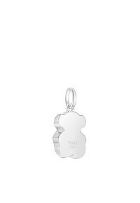 Charm en forma de oso plateado con una superficie lisa, que presenta una marca grabada en la parte posterior. Incluye un lazo para su sujeción.