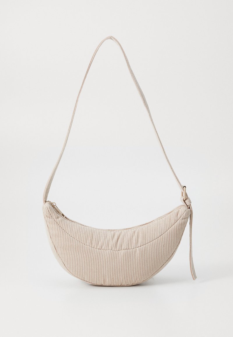 Borsa di tessuto a coste color crema, dalla forma curva, con chiusura con zip e una sottile tracolla regolabile. Texture morbida e design minimalista.
