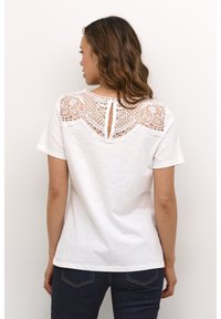 White short-sleeve t-shirt with a lace detail at the back, featuring a keyhole cutout and textured floral patterns on the lace.