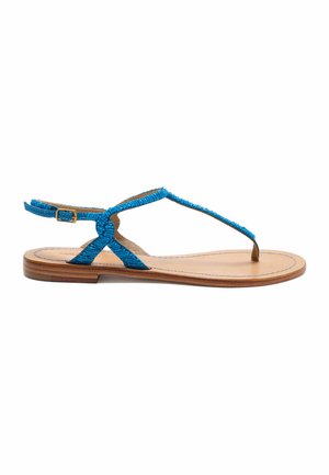 Sandalo piatto con suola color cuoio e cinturino a T azzurro brillante testurizzato con chiusura regolabile con fibbia su sfondo bianco.