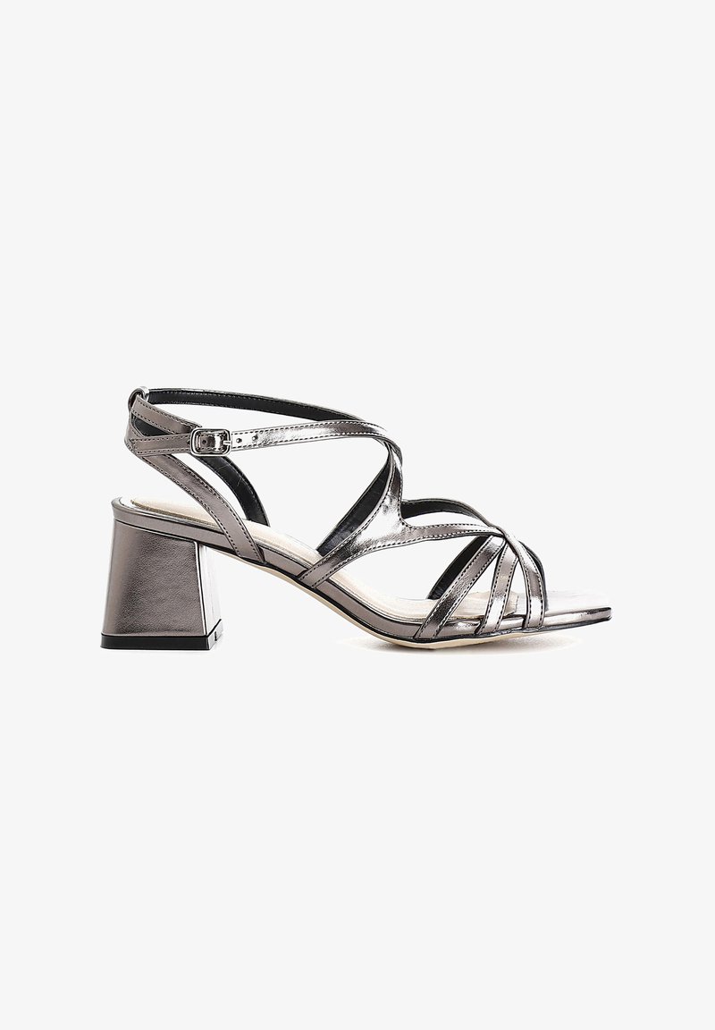 Strappy heeled sandal with metallic silver finish, block heel, open toe, and adjustable ankle strap; smooth texture and minimalist design.