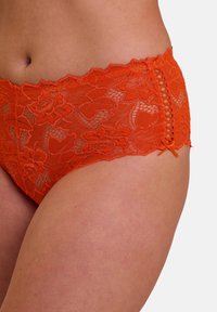 Bragas hipster de encaje naranja con patrones florales, borde ondulado y un detalle lateral con acentos de cintas entrelazadas.