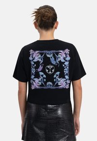 Zwarte cropped t-shirt met een bloemenontwerp in pastelkleuren aan de achterkant, met een centraal logo en korte, losse mouwen.