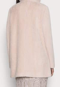 Abrigo de pelo sintético de color rosa claro con una textura suave, que presenta un corte recto, mangas largas y un collar bajo. La vista trasera muestra un diseño sin costuras.
