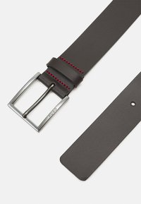 Ceinture en cuir marron foncé avec des coutures rouges, dotée d'une boucle en métal argenté et d'une texture lisse. Les extrémités sont plates et arrondies.
