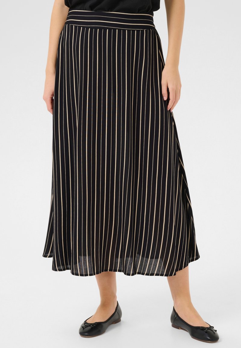 Jupe midi noire avec des rayures verticales beiges, dotée d'une texture lisse et d'une taille élastiquée, associée à des ballerines noires.