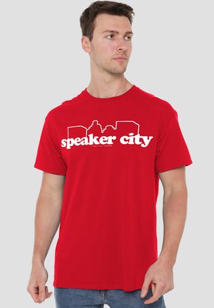 Rotes Baumwoll-T-Shirt mit einem weißen Grafikdruck von "speaker city" und Silhouetten-Designs, Rundhalsausschnitt und kurzen Ärmeln.