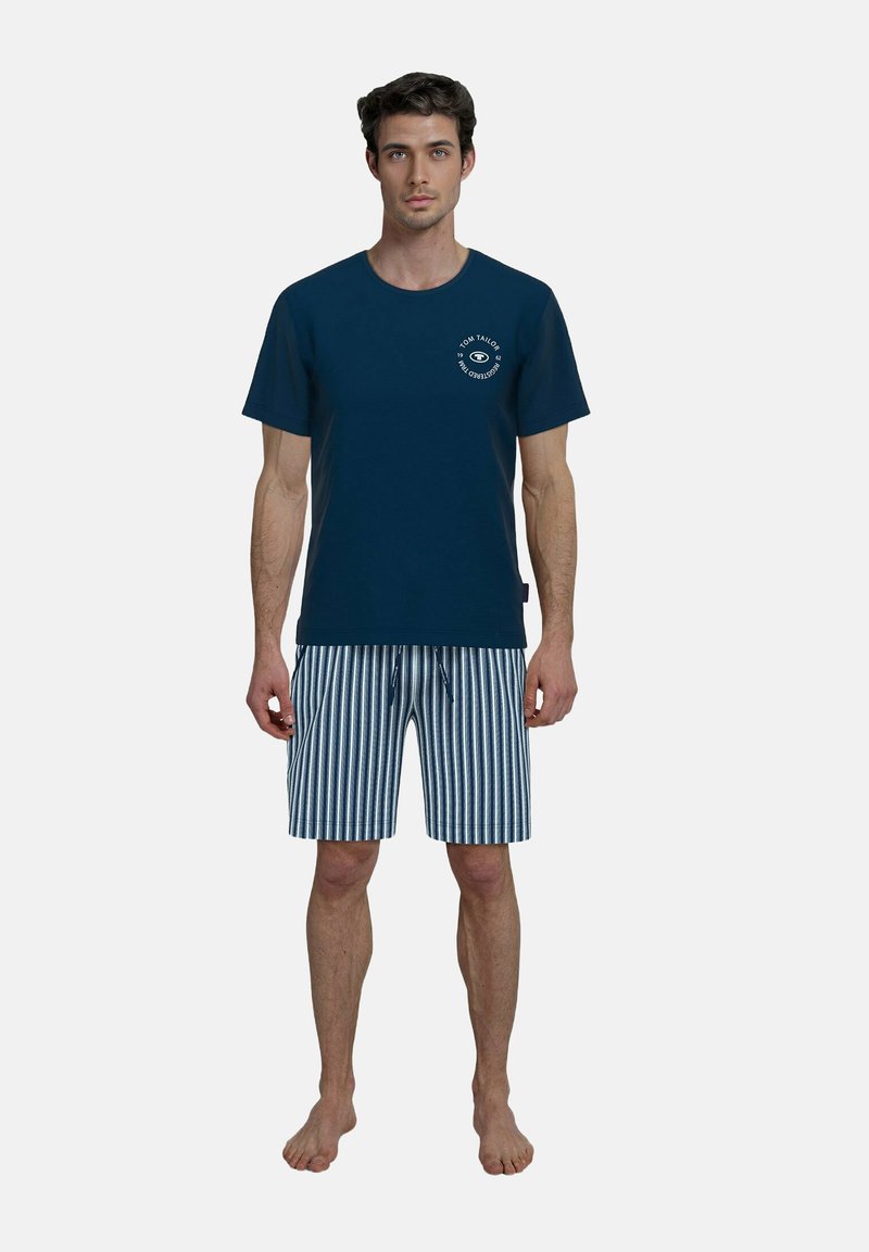 Navy Baumwoll-T-Shirt mit einem runden Logodetail, kombiniert mit gestreiften Shorts in Blau und Weiß, die einen verstellbaren Kordelzugbund haben.