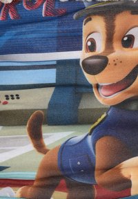 Chien de dessin animé avec un pelage brun portant un uniforme bleu et un badge. L'arrière-plan présente des éléments bleus et verts avec un design ludique.