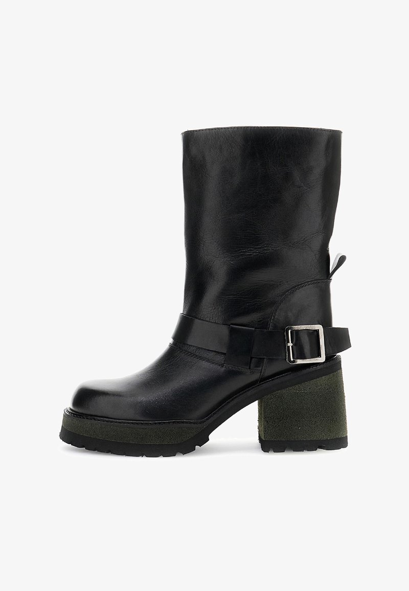 Černá kožená bota do poloviny lýtek s masivním zeleným texturovaným podpateklovým podpatkem, stříbrným zapínáním na pásku a podrážkou s drážkami na bílém pozadí.