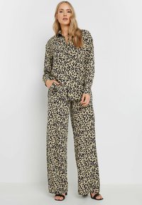 Set met luipaardprint bestaande uit een button-up shirt met lange mouwen en broek met wijde benen. De stof is lichtgewicht met een gladde textuur.
