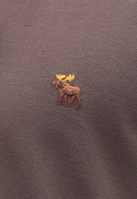 Têxtil castanho com um desenho bordado de alce em castanho escuro e galhadas amarelas, apresentando uma trama texturizada.