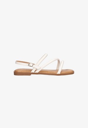 Sandalias planas blancas con tres correas delgadas y un hebilla ajustable en el tobillo. Suela marrón con una textura suave, diseño minimalista.