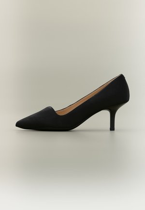 Escarpin femme en daim noir à bout pointu avec un talon bas et fin, présenté de profil sur un fond neutre.