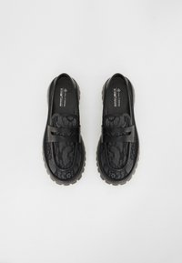 Svarta veganska loafers med en texturerad snörmönster, gummisula och dubbla remmar. Rundad form och slät innerfoder.