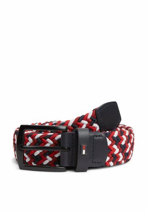 Cinturón trenzado en rojo, blanco y azul marino con hebilla metálica negra y extremo de cuero con un pequeño emblema rectangular de logo.