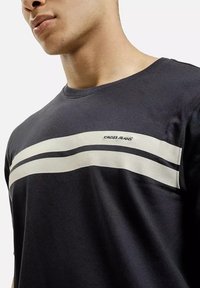 Granatowy t-shirt z krótkim rękawem o teksturowanej tkaninie, z dwoma poziomymi białymi paskami i logo "CROSS JEANS" z przodu.