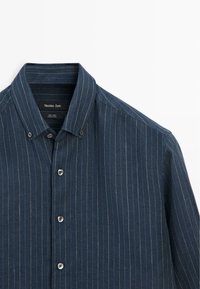 Mørkeblå herreskjorte i linned med hvide tynde striber, knapkrave og knapper foran, mærket Massimo Dutti.