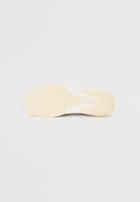 Shoe sole with a textured rubber material, features a light beige color and a smooth white accent, designed for traction and durability.