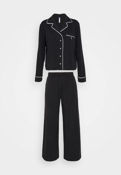 Cet ensemble en pyjama noir se compose d'un haut à manches longues avec boutons, orné de passepoils blancs et d'une poche, associé à un pantalon à jambes larges. Fabriqué en tissu doux.
