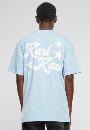 Lyseblå bomullst-skjorte med hvit grafisk tekst "Karl" og "Kari" samt stjernesymboler på baksiden, korte ermer og en avslappet passform.