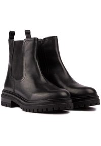 Black leather Chelsea boots with elastic side panels, pull tabs, and thick rubber soles featuring a rugged tread pattern.