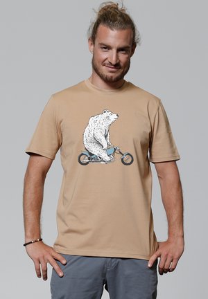 Beige T-Shirt mit einem Grafikenmotiv eines Bären, der ein blaues Fahrrad fährt. Kurze Ärmel und lockerer Schnitt, aus weichem Baumwollstoff hergestellt.