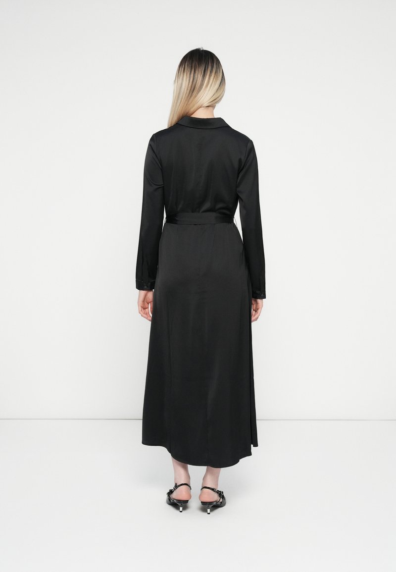 Zwarte lange mouwen jurk met een rechte silhoeët, gemaakt van gladde stof, met een tailleriem en accentuering van knopen op de manchetten.