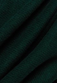 Tissu tricoté vert foncé avec une surface douce et texturée, présentant un tissage dense et cohésif. Les fibres visibles créent une apparence chaleureuse.