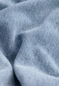 Hele hall denim kangas sujuva tekstuuriga, näidates lähedalt kudumist ja peeneid värvimuutusi. Kortsus ja pehme välimus.