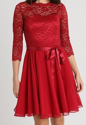 Czerwona sukienka do kolan z koronkowym górnym panelem, rękawami do łokcia i satynową kokardą w talii.