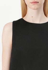 Zwarte mouwloze top met een ronde hals, gemaakt van gladde stof. Heeft een eenvoudig ontwerp dat de schone silhouet en minimalistische stijl benadrukt.